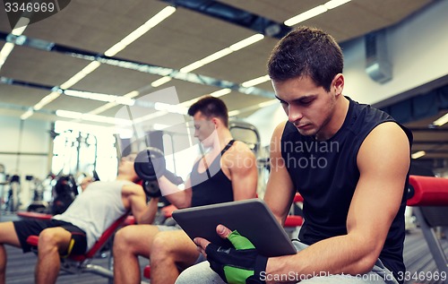 Image of group of men with tablet pc and dumbbells in gym