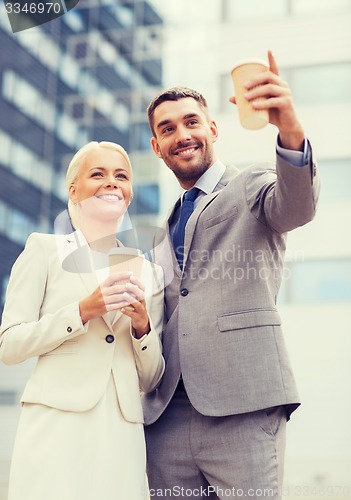 Image of smiling businessmen with paper cups outdoors