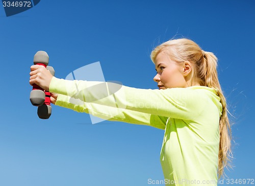 Image of sporty woman with light dumbbells outdoors