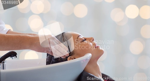 Image of happy young woman having salon hair wash