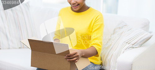 Image of happy african young woman with parcel box at home