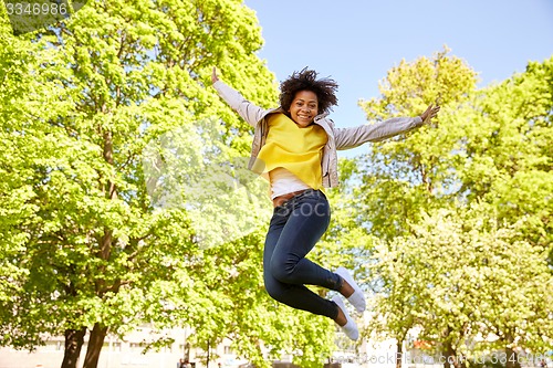 Image of happy african american young woman in summer park