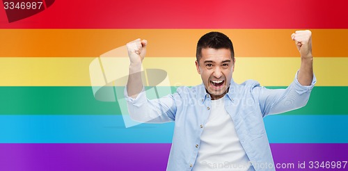 Image of angry man with raised hands over rainbow flag