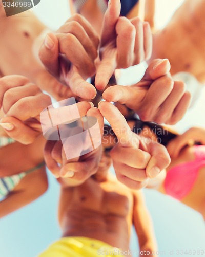 Image of close up of friends in circle on summer beach