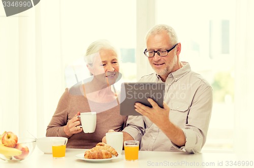 Image of happy senior couple with tablet pc at home