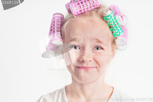 Image of Portrait of emotional cute little girl with curler