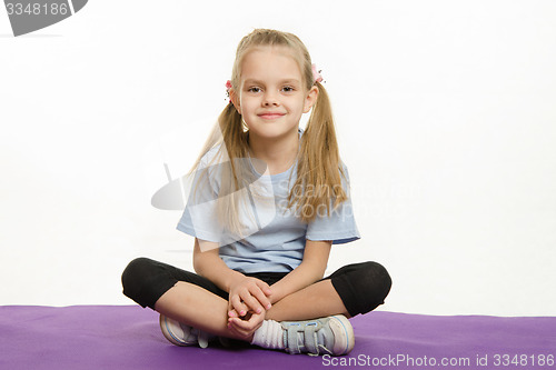 Image of Six year old girl athlete sitting on a rug