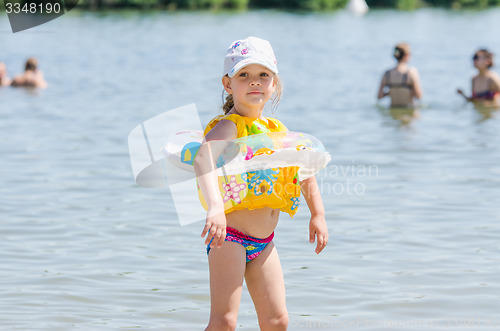 Image of Four-year girl on the beach wearing a life jacket and circle