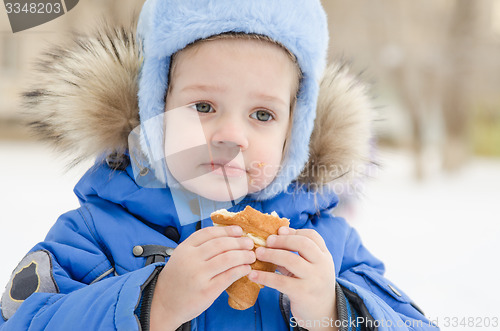 Image of The girl eats a bun in street in winter
