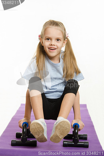 Image of Six year old girl on a rug engaged with stops for push-ups