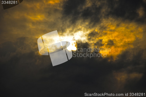 Image of A dark sky with clouds and sun.