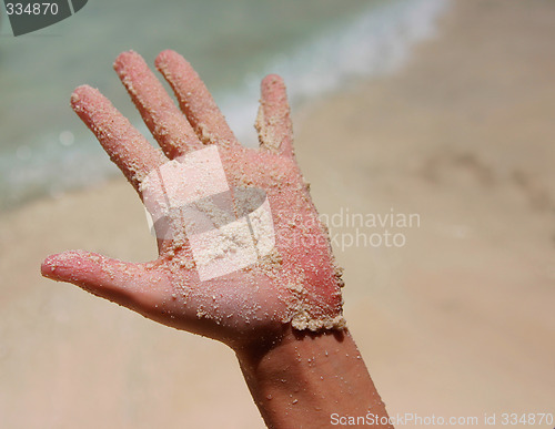 Image of a white wet sand in sunburned hand