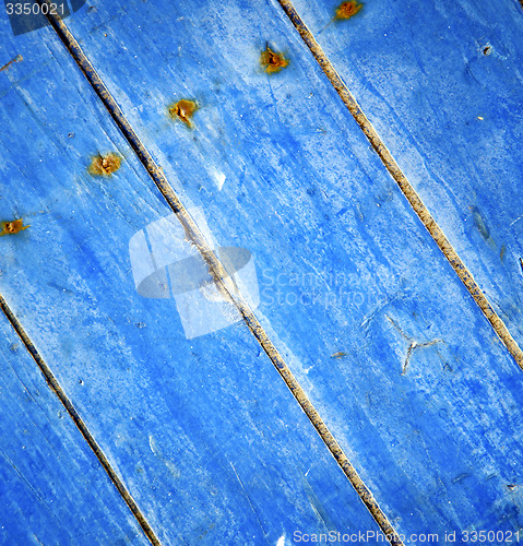 Image of dirty stripped paint in the blue wood door and rusty nail