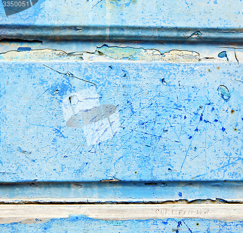 Image of stripped paint in the blue wood door and rusty nail