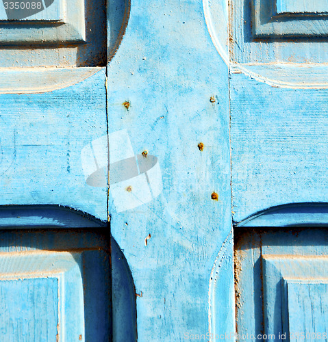 Image of dirty stripped paint in the blue wood door and rusty nail