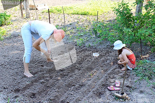 Image of mother and her daughter plant seeding-onion