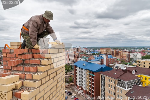 Image of Bricklayer works on high house construction