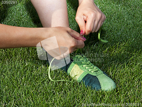 Image of woman ties laces on sport shoes