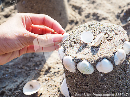 Image of Person creating a sand castle with white clams