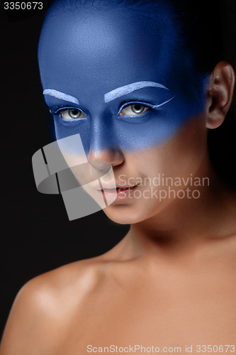 Image of Portrait of a woman who is posing covered with blue paint