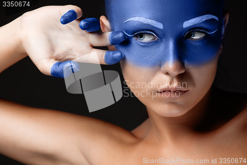 Image of Portrait of a woman who is posing covered with blue paint