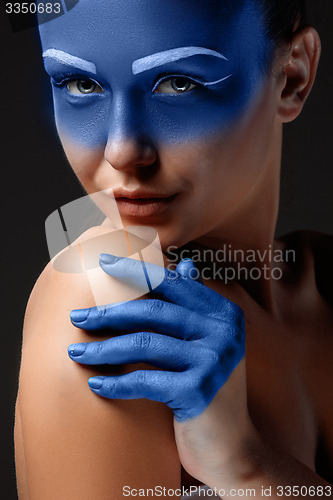 Image of Portrait of a woman who is posing covered with blue paint