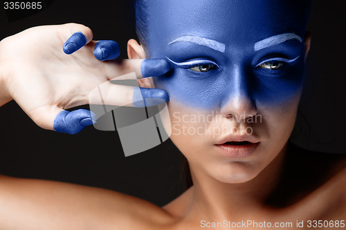 Image of Portrait of a woman who is posing covered with blue paint