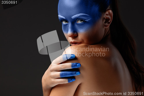 Image of Portrait of a woman who is posing covered with blue paint