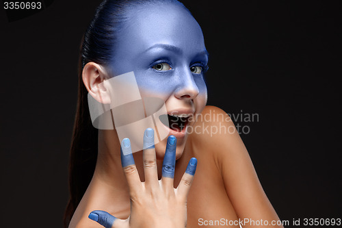 Image of Portrait of a woman who is posing covered with blue paint