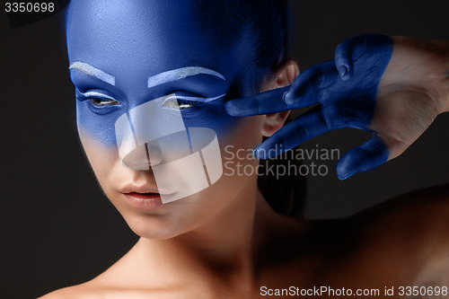 Image of Portrait of a woman who is posing covered with blue paint