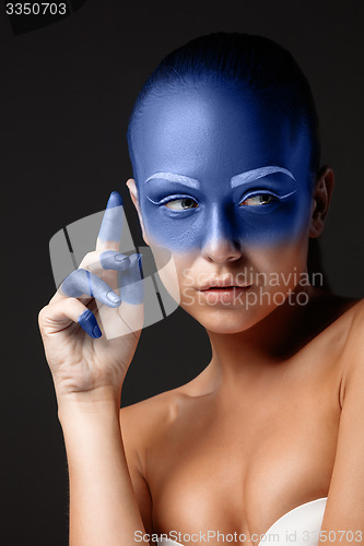 Image of Portrait of a woman who is posing covered with blue paint