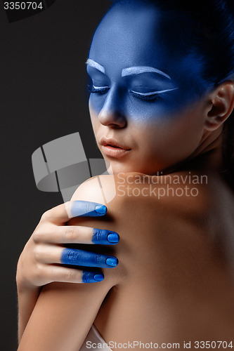 Image of Portrait of a woman who is posing covered with blue paint