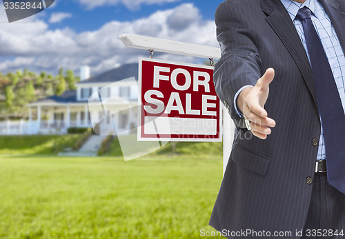 Image of Agent Reaches for Handshake, Sale Sign and House Behind