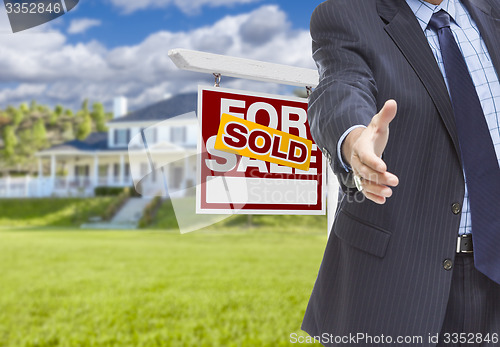 Image of Agent Reaches for Handshake, Sold Sign and House Behind