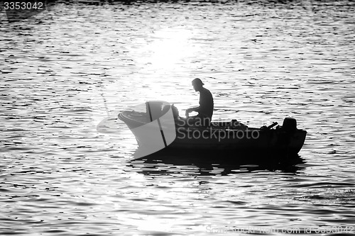 Image of Man in motor boat at sunset bw