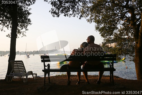 Image of Couple sitting on bench at sunset