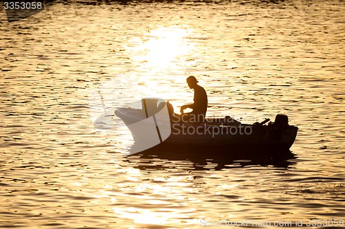 Image of Man in motor boat at sunset 