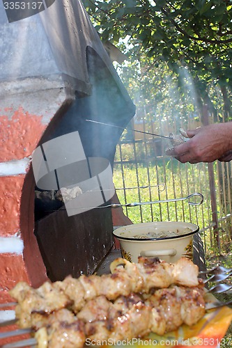 Image of human hands roasting appetizing barbecue on fire