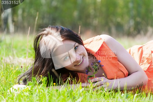 Image of Pretty girl in orange dress laying on grass