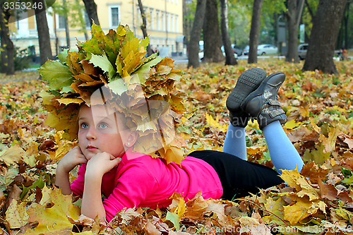 Image of little girl lying on the yellow leaves