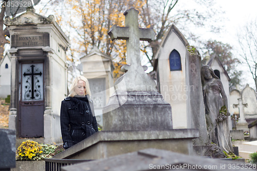 Image of Solitary woman visiting relatives grave.