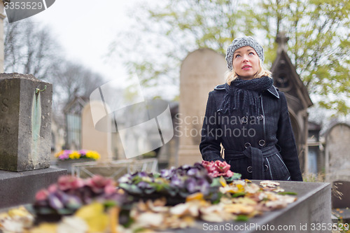 Image of Solitary woman visiting relatives grave.