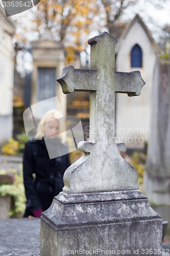 Image of Solitary woman visiting relatives grave.