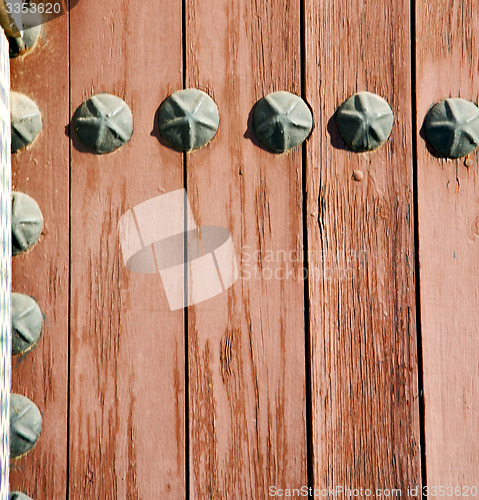 Image of nail dirty stripped paint in the brown wood door and rusty yello
