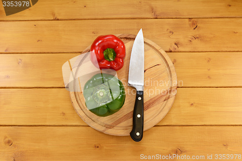 Image of Red and green peppers with a knife on a chopping board 