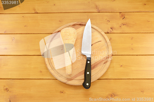 Image of Raw parsnip with a knife on a wooden board