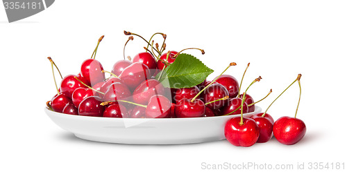 Image of Sweet cherries with leaf on white plate and three near