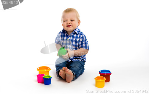 Image of Happy baby in a plaid shirt with toys. studio