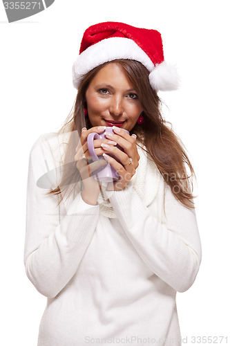 Image of Cold young woman in a Santa hat sipping coffee tea