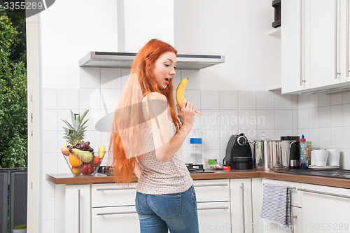 Image of Happy Woman Holding Banana Dancing in the Kitchen